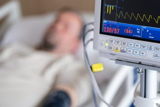 a man laying in a hospital bed next to a monitor