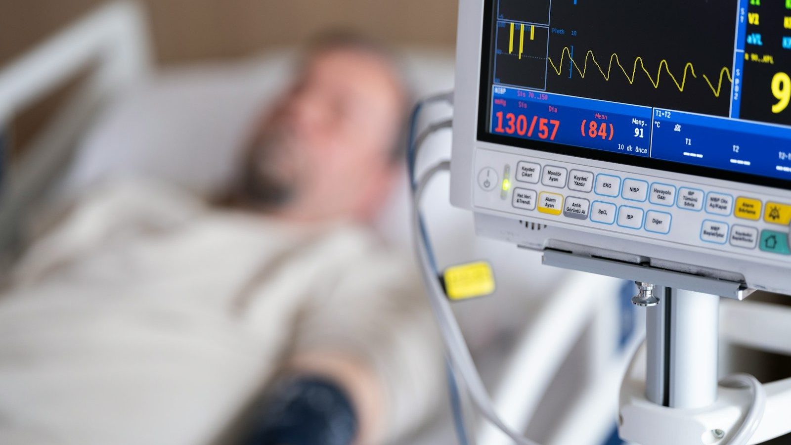 a man laying in a hospital bed next to a monitor